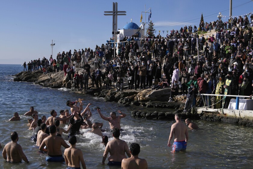 Pilgrims jump to catch the cross during a water blessing ceremony marking the Epiphany celebrations at Piraeus port, near Athens, Thursday, Jan. 6, 2022. Celebrations to mark the Christian holiday of Epiphany were canceled or scaled back in many parts of Greece Thursday as the country struggles with a huge surge in COVID-19 infections driven by the omicron variant. (AP Photo/Thanassis Stavrakis)