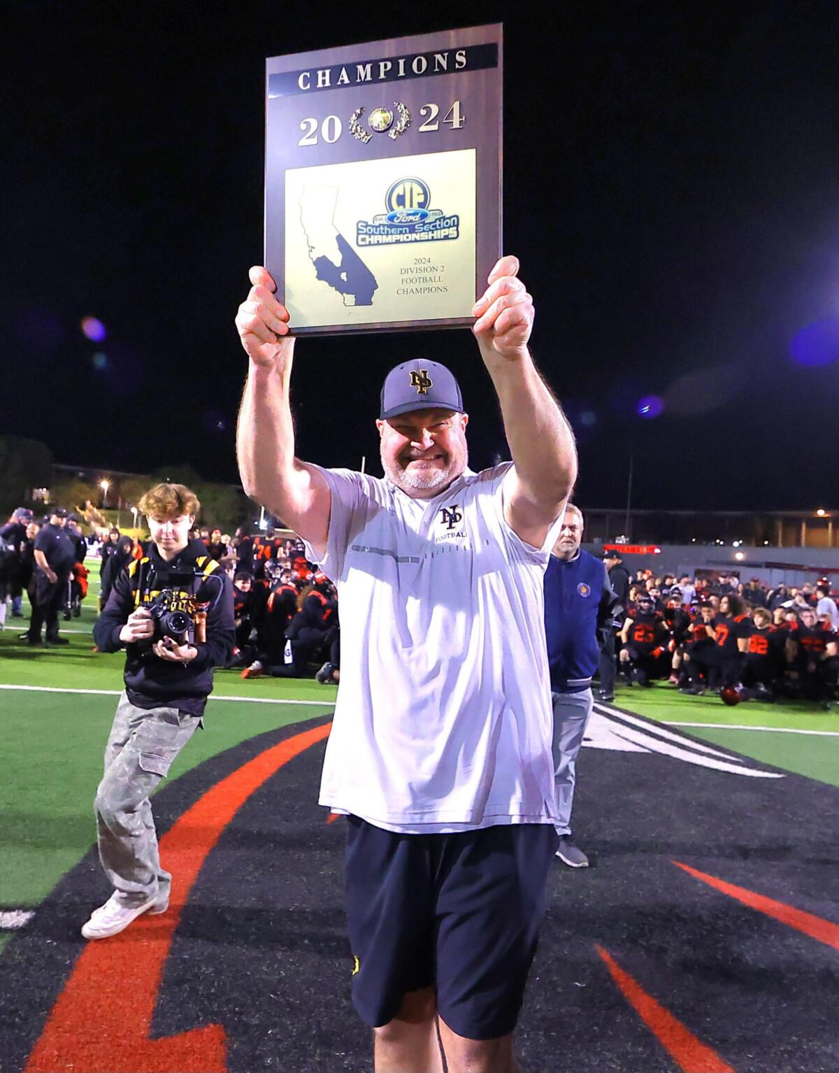 Newbury Park coach Joe Smigiel holds up the Division 2 championship plaque.