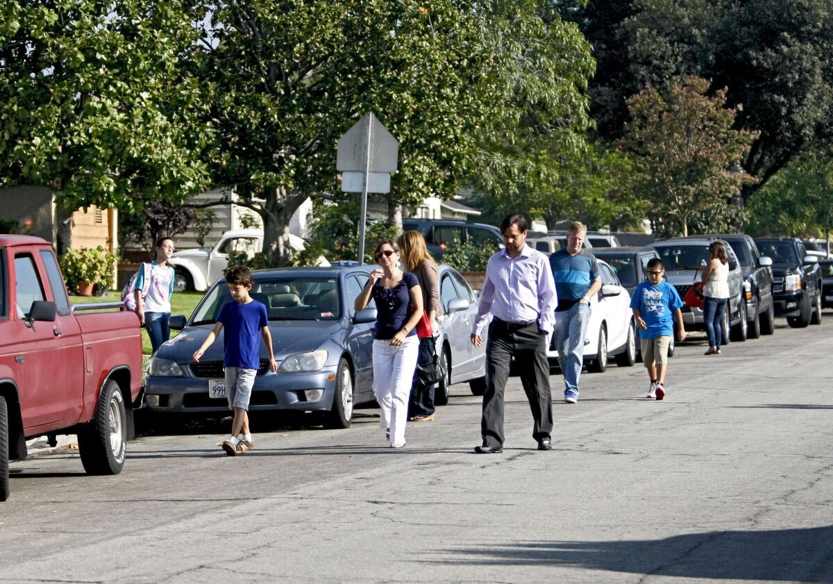 Because there are no sidewalks and the public right of way is blocked with bushes and fences at many homes, parents and students walk along the road on the 1800 block of Screenland Drive as they head to orientation day for new students at Burbank Middle School in Burbank on Thursday, August 15, 2013. A woman walking her child to school commented that it was "strange" there were no sidewalks.