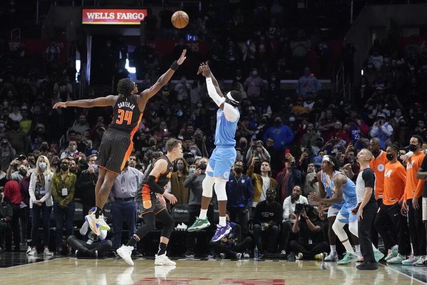 Clippers guard Reggie Jackson makes a shot over Magic center Wendell Carter Jr. (34) late in the game Dec. 11, 2021.