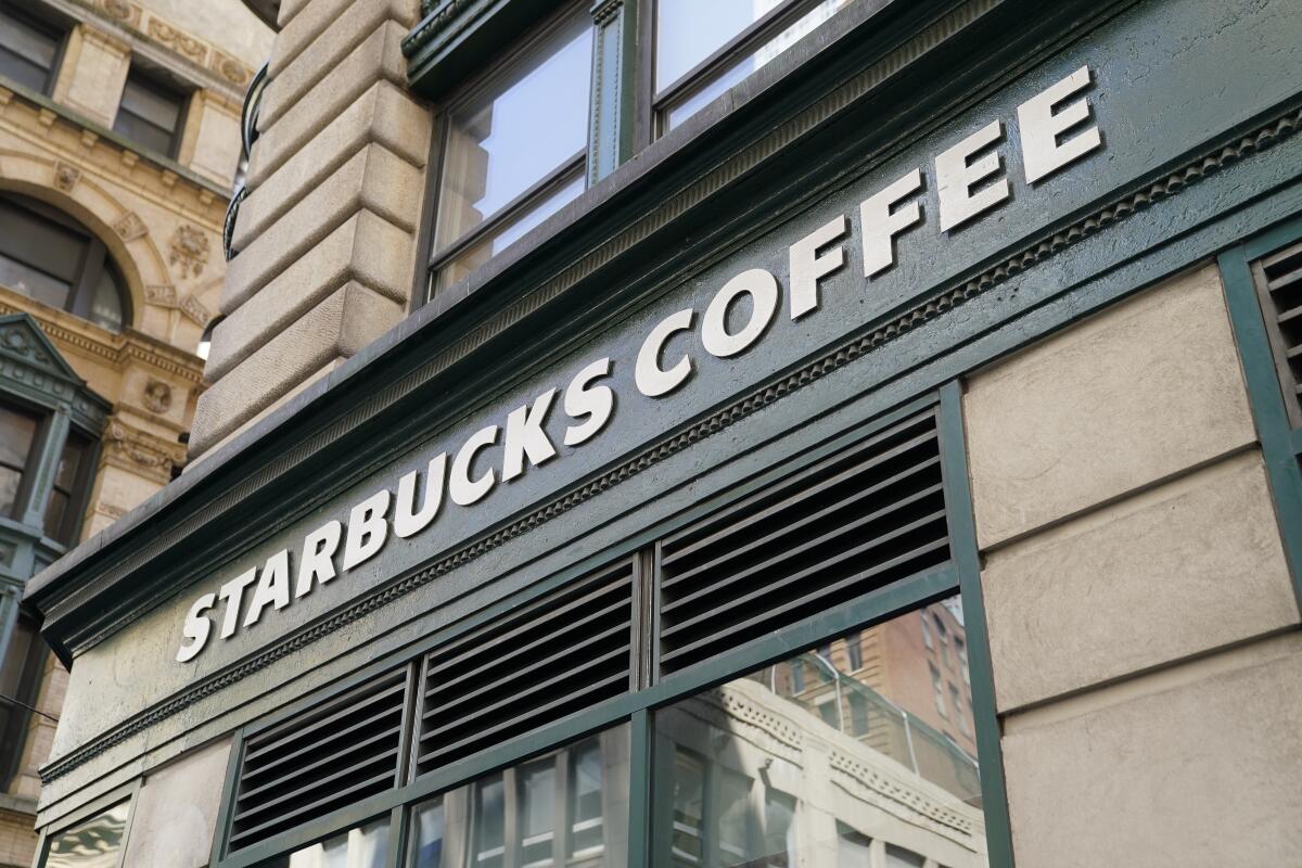 A Starbucks sign sits above a store entrance in the Financial District of Lower Manhattan