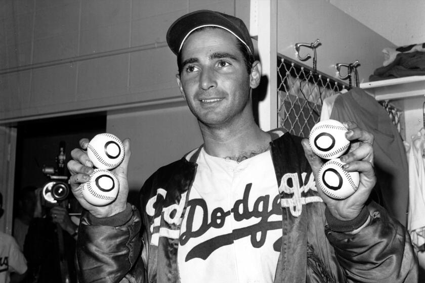 Sandy Koufax, pitcher of the Los Angeles Dodgers, holds up four baseballs in Los Angeles, Ca. on Sept. 10, 1965. It is the day after he pitched a perfect game for a 1–0 win against the Chicago Cubs, making him the first major leaguer to pitch four no–hit games. (AP Photo)