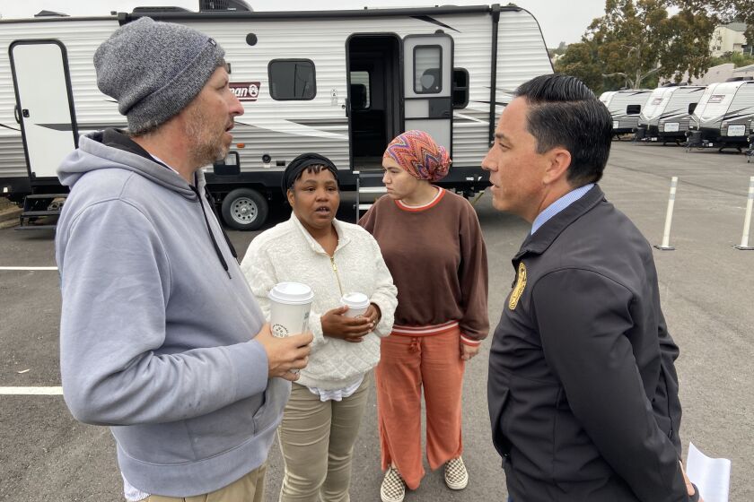 San Diego Mayor Todd Gloria speaks with Michael Johns and others among in a trailer at a new safe parking lot in Clairemont. 