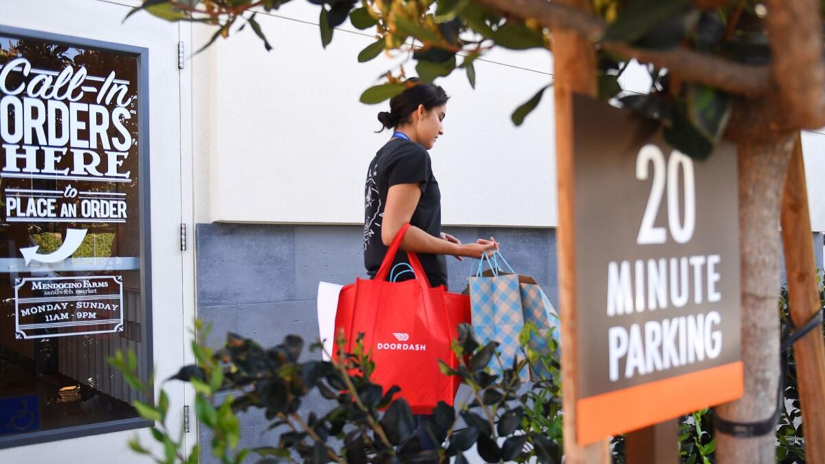 A worker with food delivery service DoorDash carries several bags after picking up an order.
