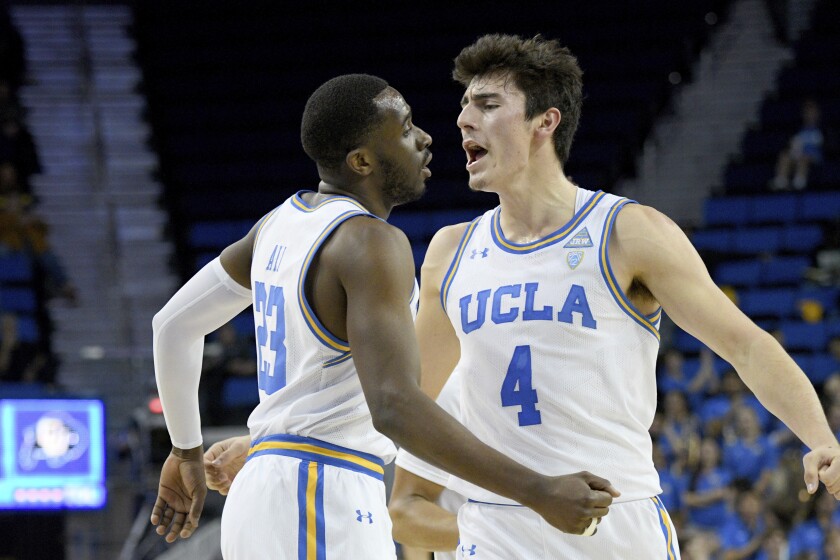 UCLA guard Prince Ali, left, celebrates with guard Jaime Jaquez Jr. during a timeout after making a 3-point shot during the first half against Colorado on Thursday at Pauley Pavilion.