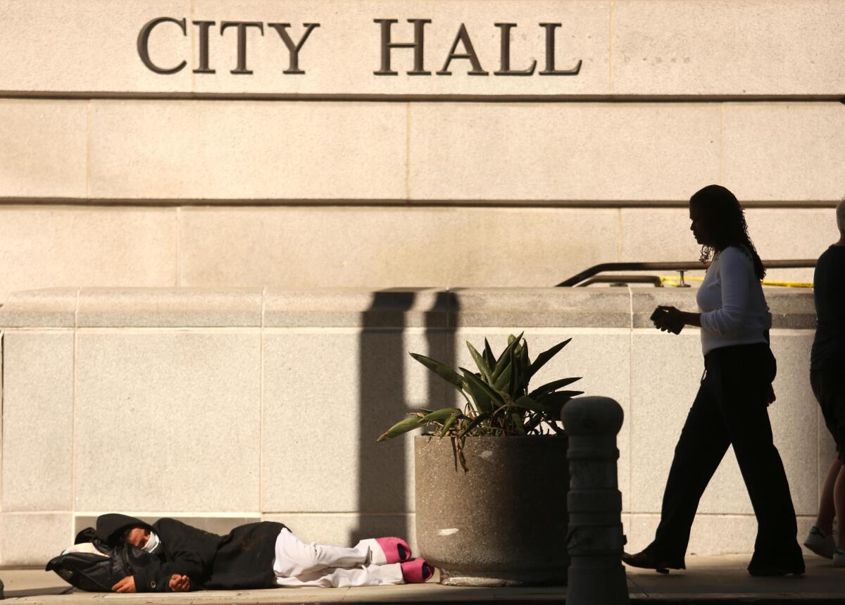 A person sleeps along the sidewalk outside Los Angeles City Hall on Oct. 19. 