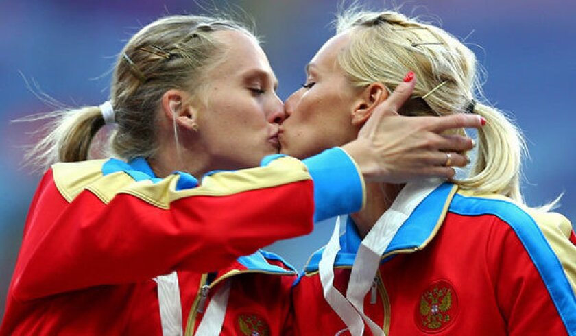 Russian sprinters Kseniya Ryzhova and Yulia Guashcina share a kiss on the victory stand after their team won the 400-meter relay at the track and field world championships in Moscow over the weekend.