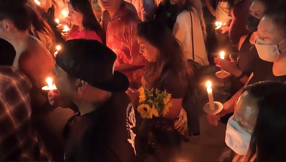 Mourners hold candles at a vigil on July 31 for theater shooting victims Anthony Barajas and Rylee Goodrich.