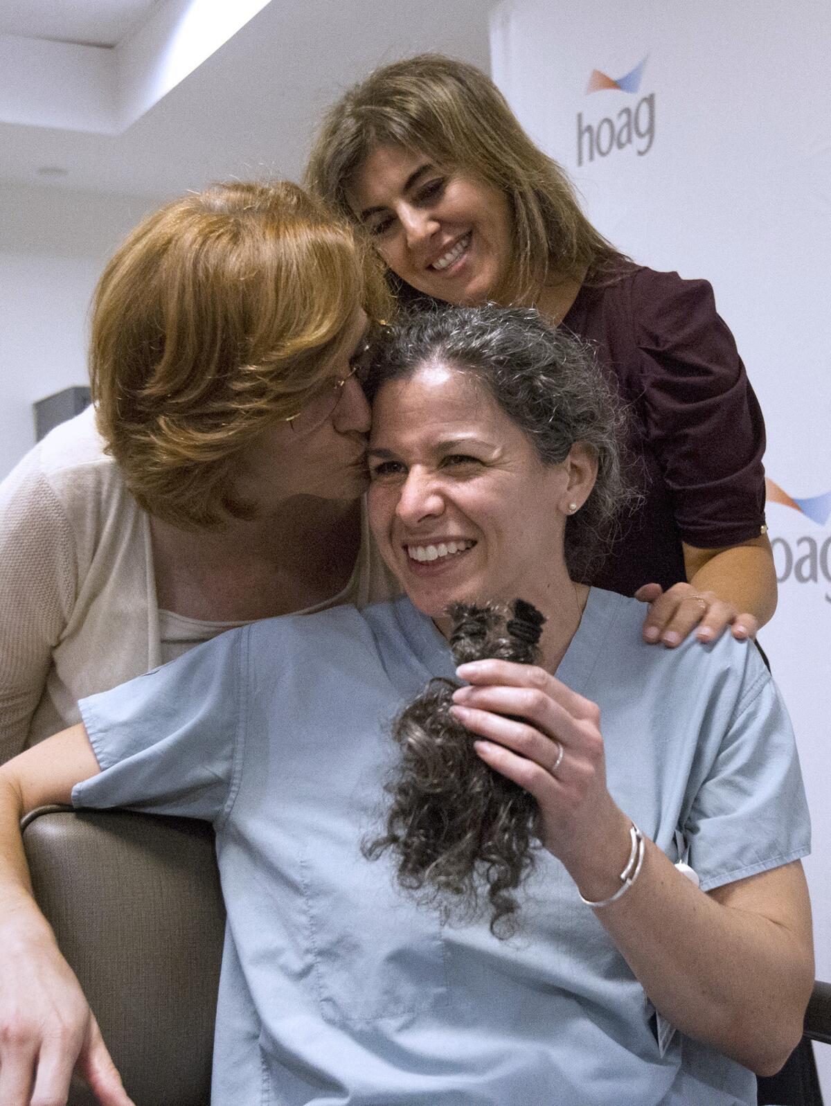 Dr. Lisa Guerra, bottom, a Hoag Breast Center surgeon, holds up 8 inches of her hair that top donors Margie Gollihugh, left, and Niloofar Fakhimi, top, help cut off on Friday at Hoag Cancer Center in Newport Beach. Dr. Guerra raised more than $15,000 for the Susan G. Komen organization's efforts against breast cancer. She pledged at this year's Komen Race for the Cure that the top donor could cut off her ponytail, which she would donate to Pantene Beautiful Lengths, who makes wigs for women with cancer.