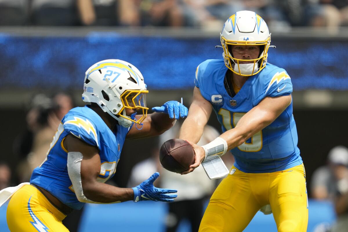 Chargers quarterback Justin Herbert (10) hands off the ball to running back J.K. Dobbins (27).