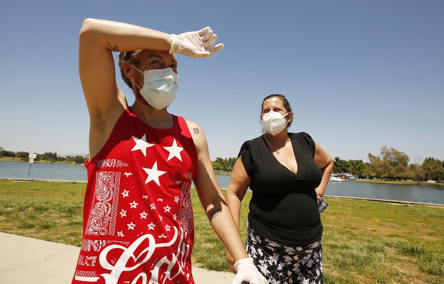 Trevor Voeltner wipes his brow as he walks with wife Betty Voeltner and their 2-year-old son Carte