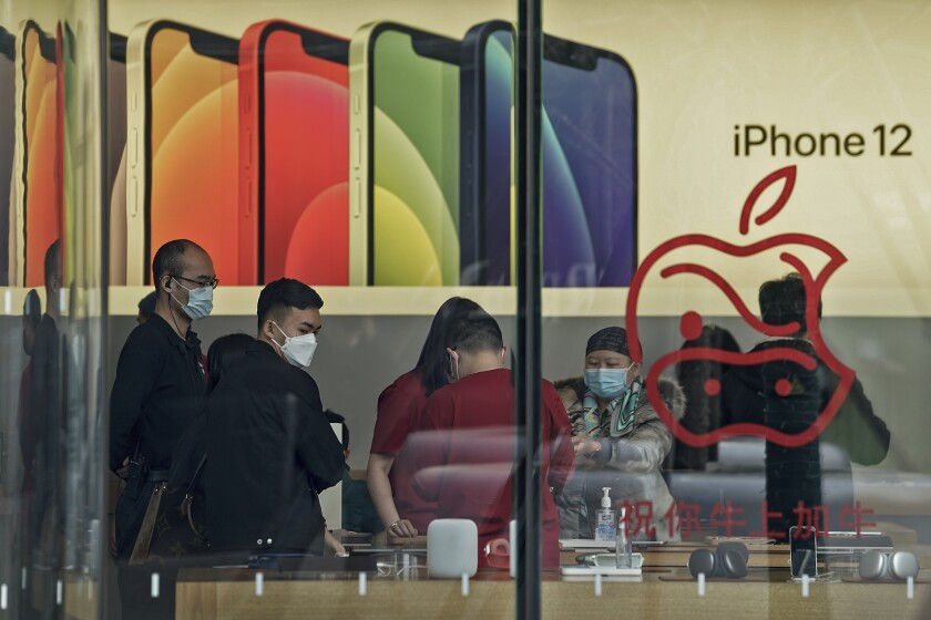 People wearing face masks to help curb the spread of the coronavirus look at iPad devices at an Apple store at the capital city's popular shopping mall in Beijing on Wednesday, Feb. 24, 2021. (AP Photo/Andy Wong)