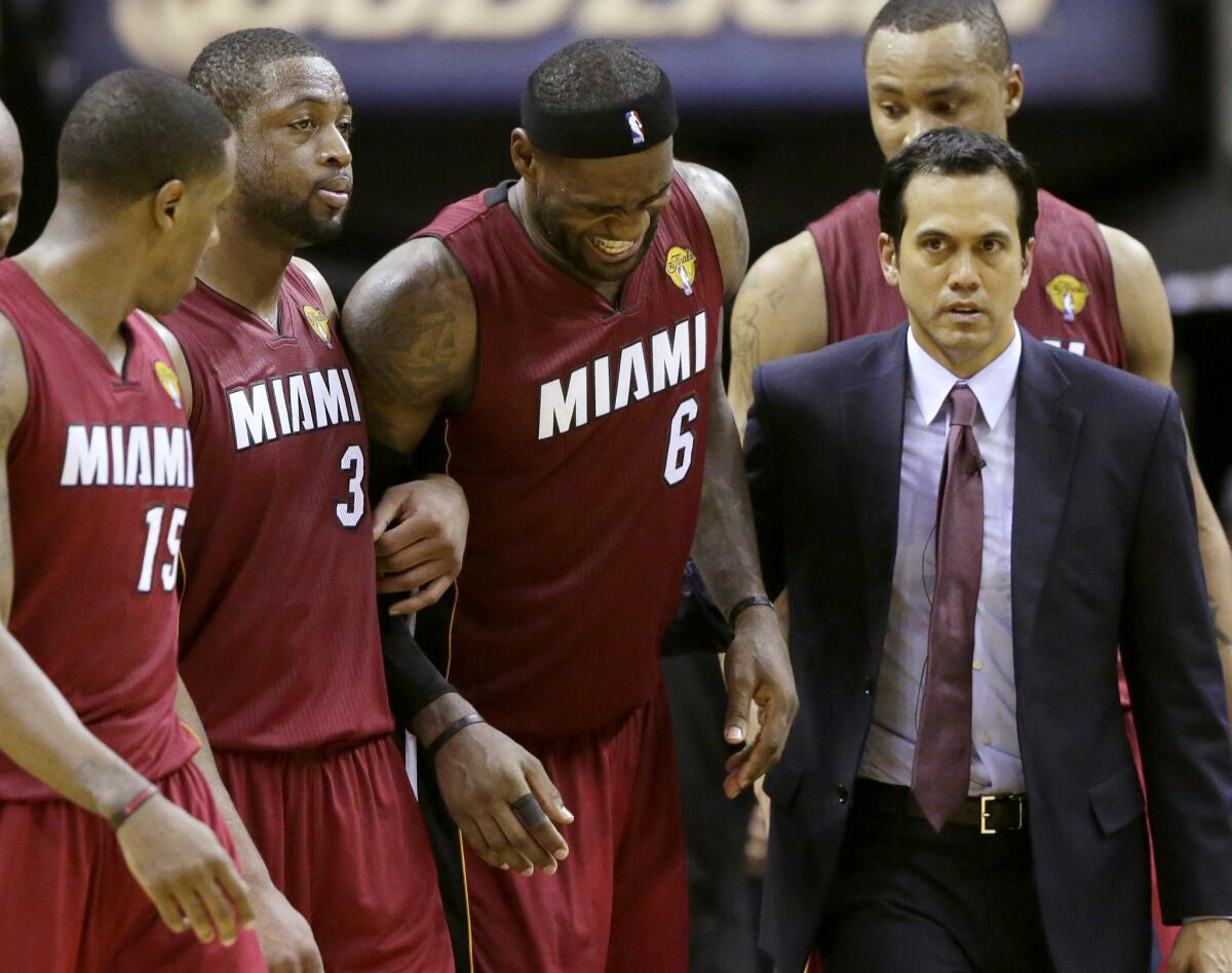 Miami Heat forward LeBron James is helped from the court by guard Mario Chalmers (15), guard Dwyane Wade (3) and Coach Erik Spoelstra.