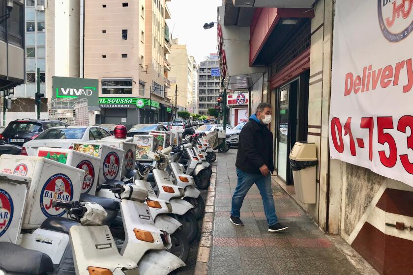 A staff member walks by Barbar's swarm of scruffy-looking white scooters.