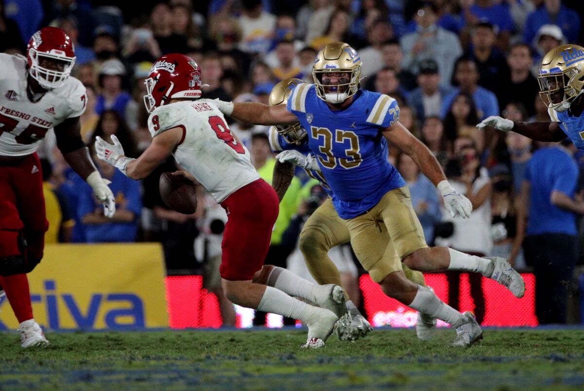 Fresno State quarterback Jake Haener eludes the oncoming rush of UCLA linebacker Bo Calvert.