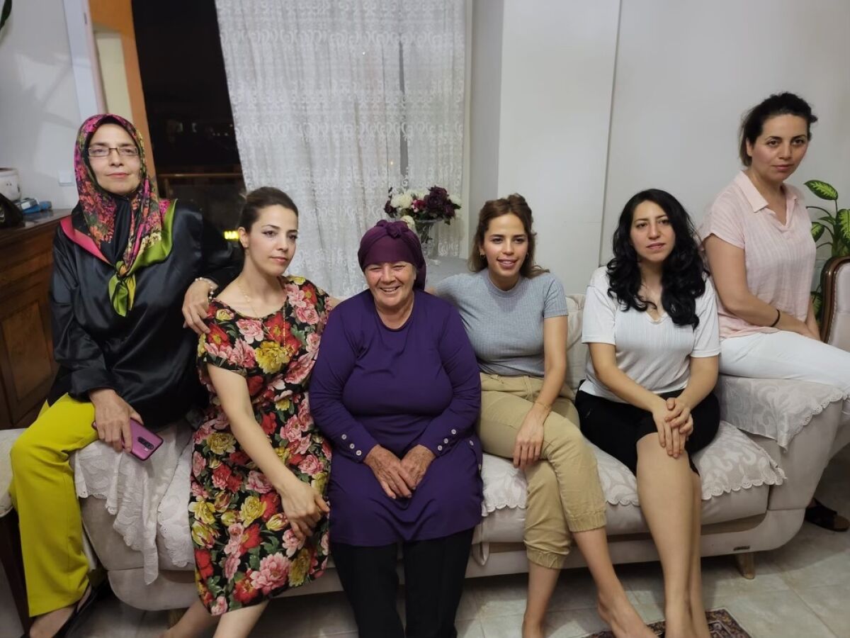 Six women are seated on a sofa