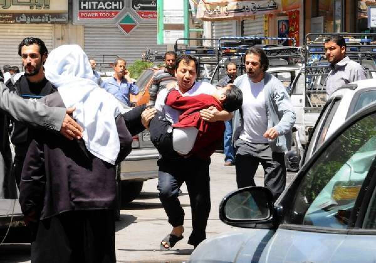 A man runs with one of the injured after an explosion in Damascus, the Syrian capital. The official Syrian news agency reported that at least 13 people were killed and more than 70 were injured.
