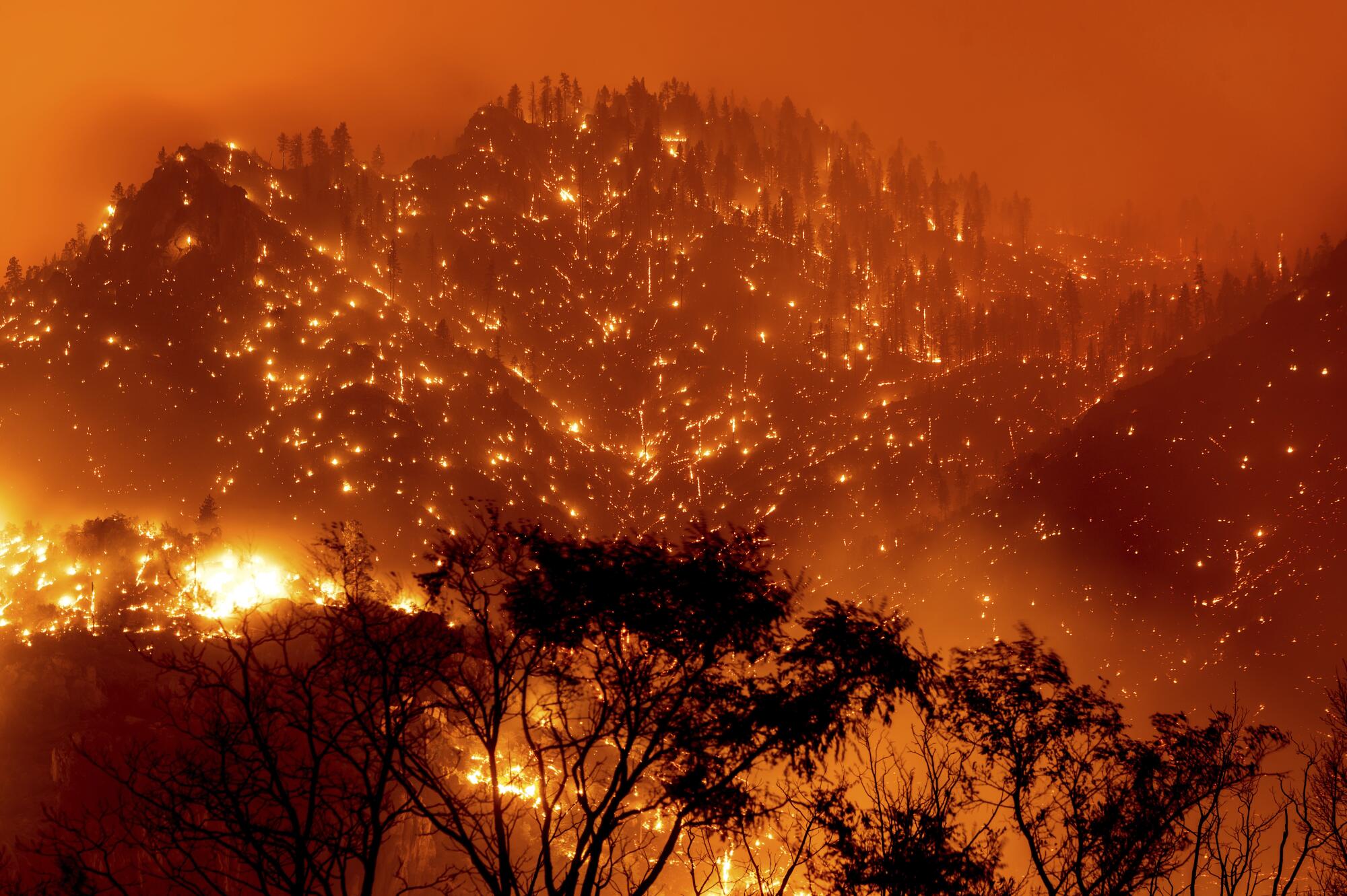 In this long exposure photo, embers illuminate the hillsides as the Dixie Fire burns near Milford.