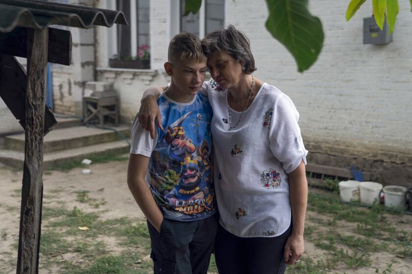 Shevchenkove, Ukraine - July 19: Tymophiy is hugged by his aunt Olena Streelets on Tuesday, July 19, 2022 in Shevchenkove, Ukraine. Twelve-year-old Tymophiy, from a village outside Kyiv, lost his mother and stepfather in the war's earliest days. They were killed in their car by fire from Russian troops. Now he and his 6-year-old half-brother, Seraphim, are starting new lives with their aunt and uncle, who want to become both boys' adoptive parents. Tymophiy has documented some of his experiences in a wartime diary, including not learning of his mother and stepfather's deaths until days after the fact.(Kyrylo Svietashov / For the Times)