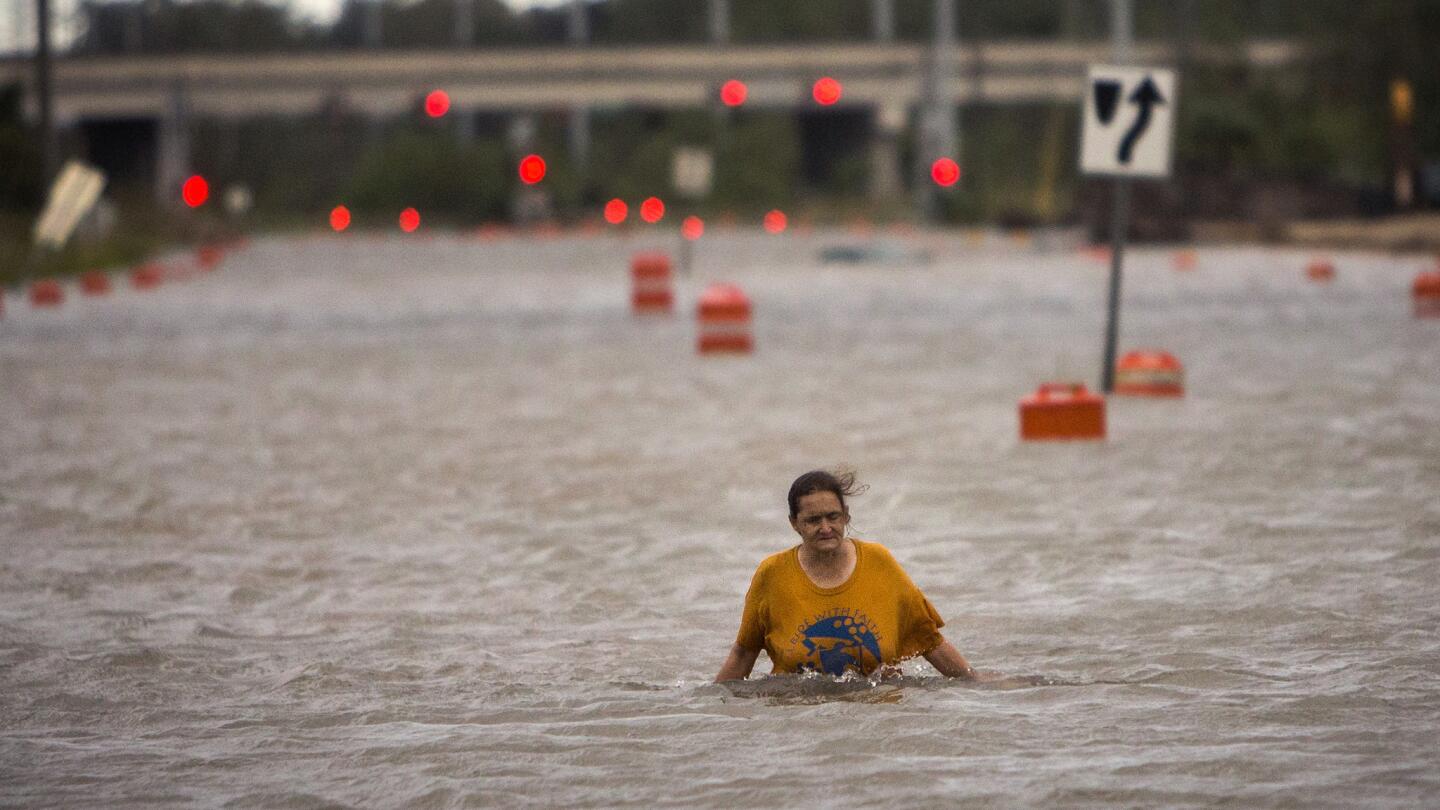 A woman who identified herself as Valerie walks along flooded President Street after leaving her homeless camp after Hurricane Matthew caused flooding, Saturday, Oct. 8, 2016, in Savannah, Ga. Matthew plowed north along the Atlantic coast, flooding towns and gouging out roads in its path.