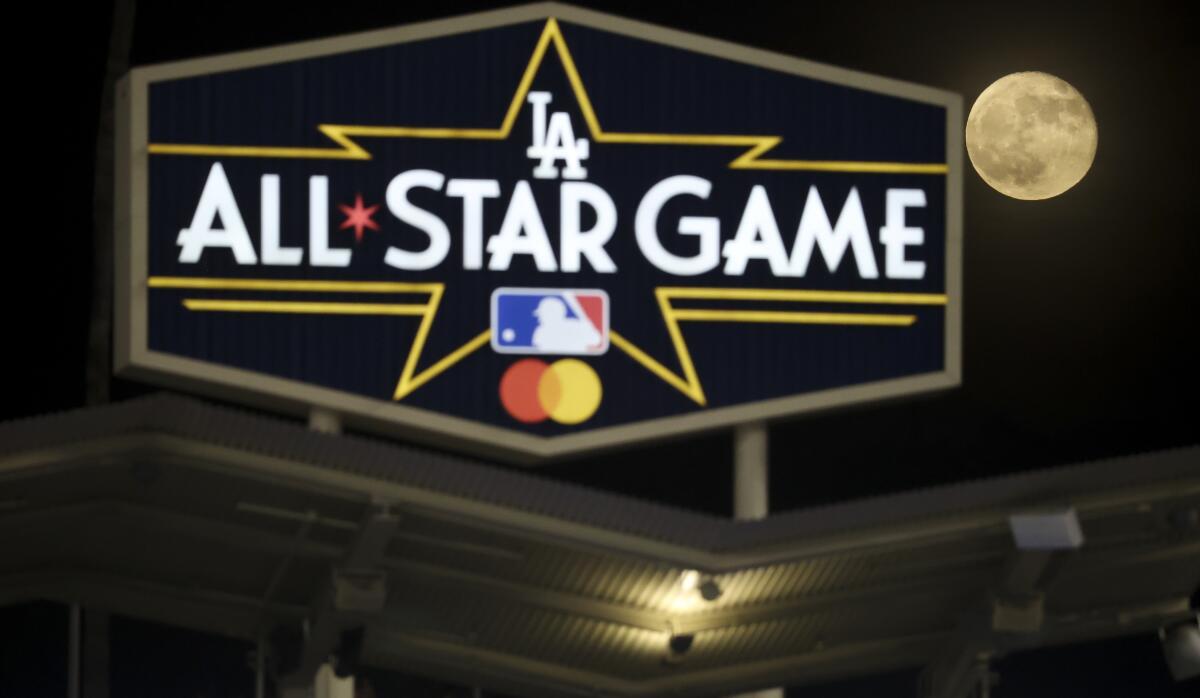 The moon rises behind a sign at Dodger Stadium promoting the 2022 MLB All-Star Game.