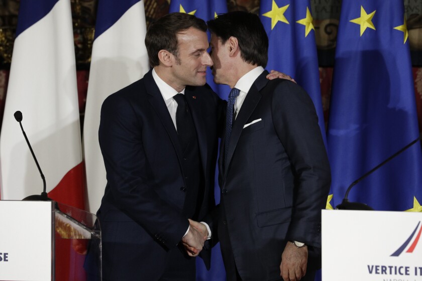 French President Emmanuel Macron, left, puts his arm around the shoulder of Italian Premier Giuseppe Conte and gives him a kiss on both cheeks. 