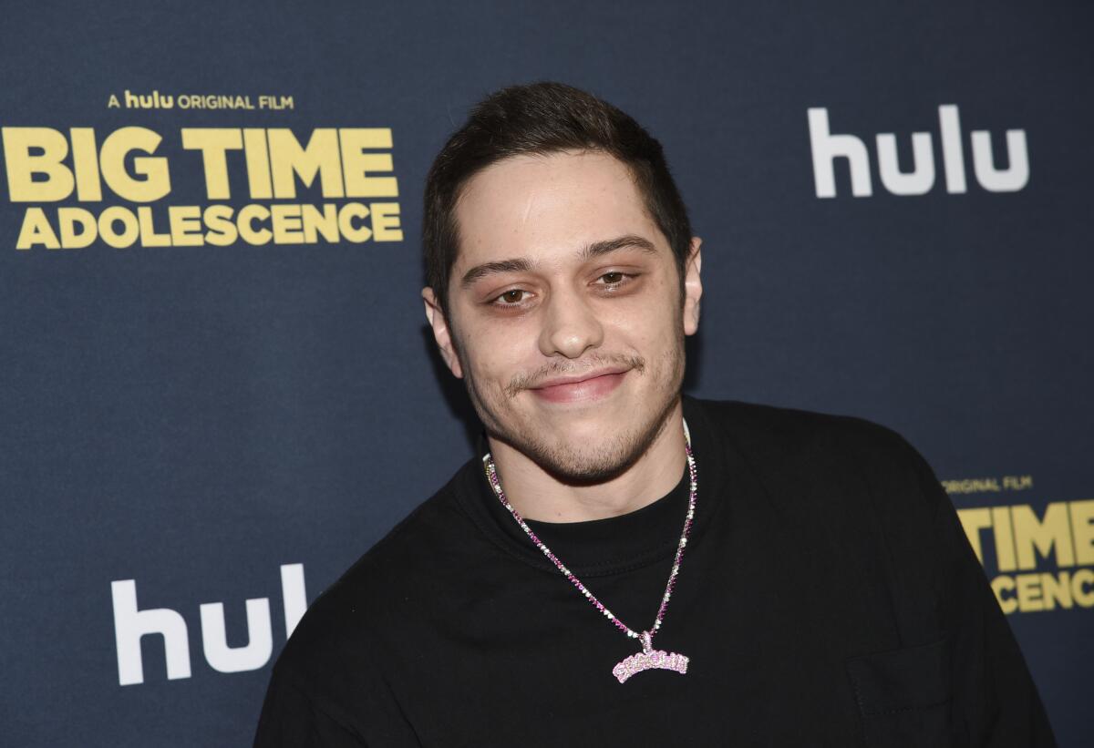 Pete Davidson in a black sweater and chain.