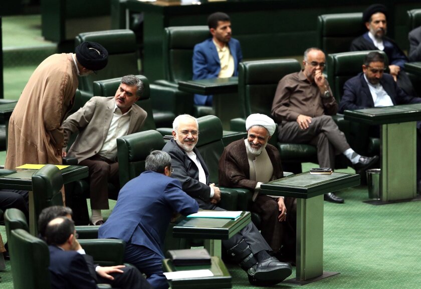 Iranian Foreign Minister Mohammad Javad Zarif, center, smiles as he chats with lawmakers during a session in Tehran on Oct. 13, 2015, in which parliament approved its nuclear deal with world powers.