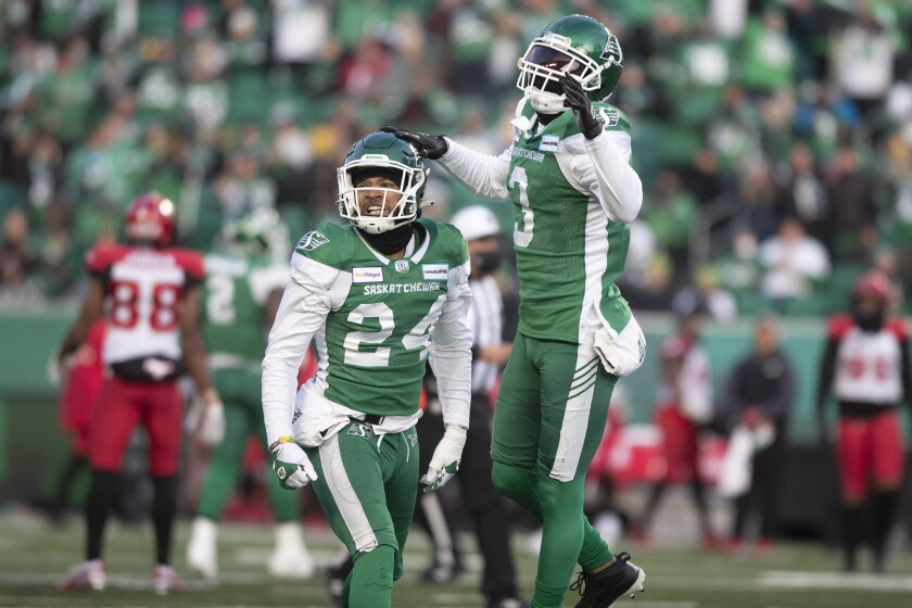 Saskatchewan Roughriders defensive back Damon Webb (24) and teammate Nick Marshall (3) celebrate after a referee makes a call in their favor during the first half of a CFL football game against the Calgary Stampeders Sunday, Nov. 28., 2021 in Regina, Saskatchewan. (Kayle Neis/The Canadian Press via AP)