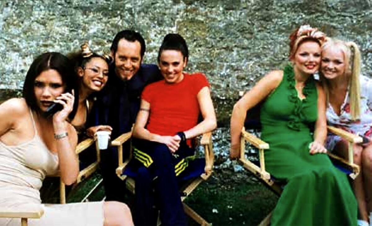 A man poses with the girl group The Spice Girls on a movie set.