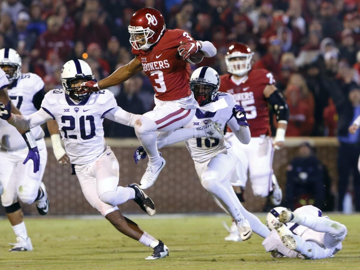 Oklahoma's Sterling Shepard (3) leaps to avoid TCU's Montrel Wilson (20) and others on Saturday.