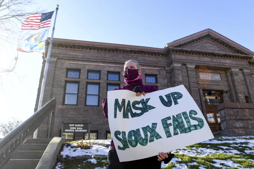 Jenae Ruesink holds a sign demanding a mask mandate from city council on Monday, Nov. 16, 2020 outside Carnegie Town Hall in Sioux Falls, S.D. (Erin Bormett/The Argus Leader via AP)