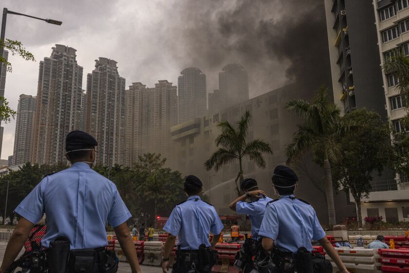 Police officers patrol as a warehouse burns in Cheung Sha Wan in Hong Kong, Friday, March 24, 2023. Hong Kong firefighters were battling a blaze Friday at a warehouse that forced 3,400 people to evacuate, including students, police said. (AP Photo/Louise Delmotte)