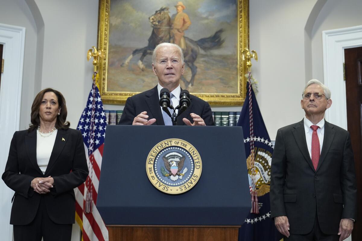 President Biden speaks at a White House lectern flanked by Vice President Kamala Harris, left, and Atty. Gen. Merrick Garland