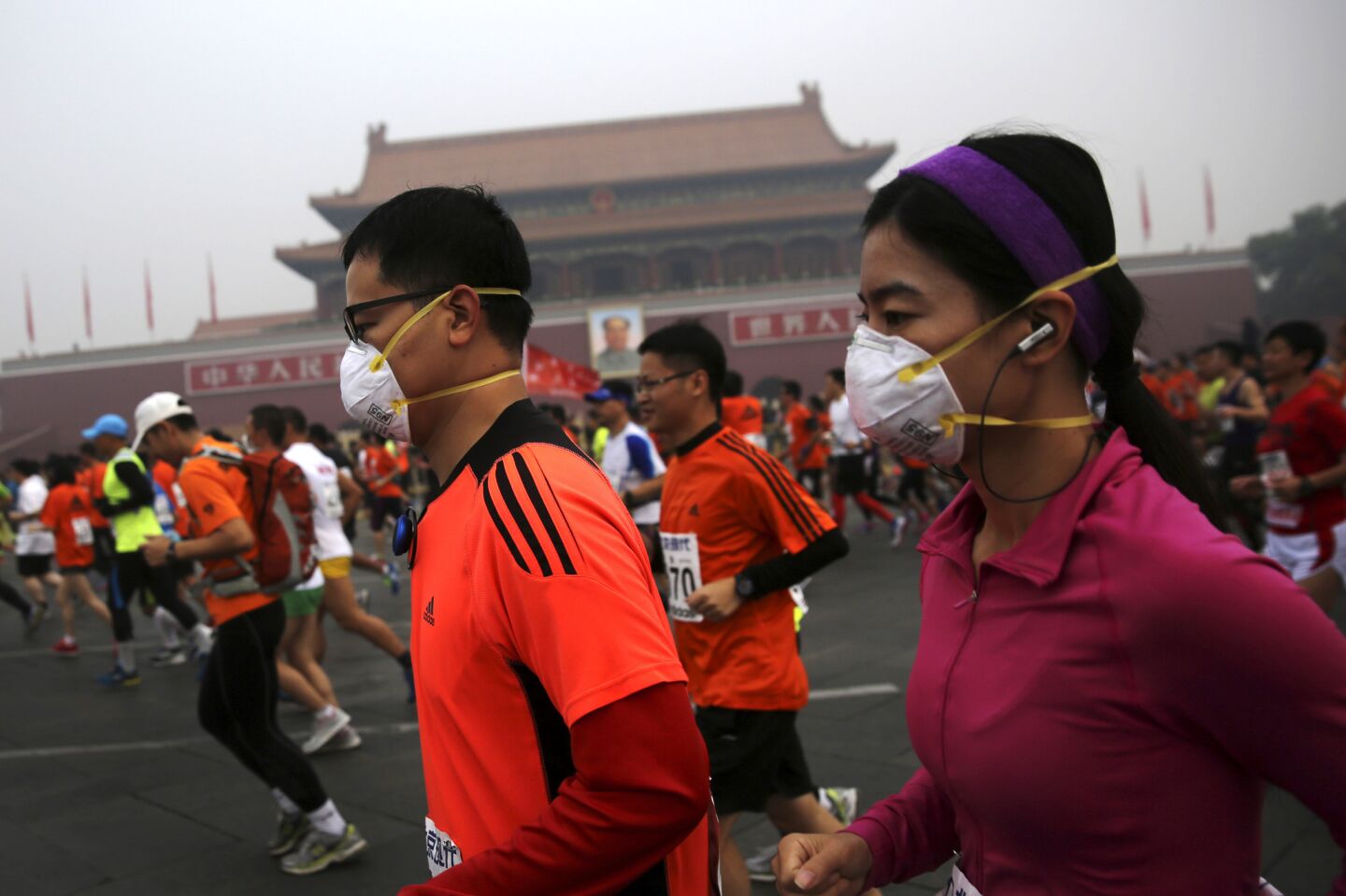 Runners, some wearing masks, jog past Tiananmen Gate.