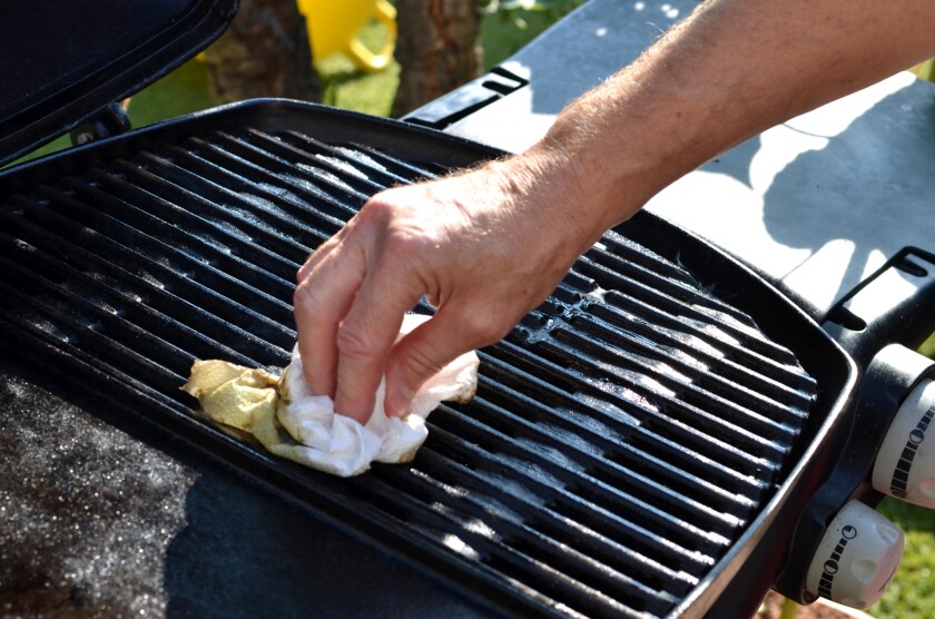 A person uses a cloth to wipe off their grill.