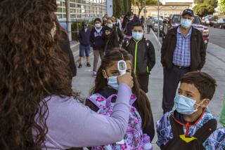 South Gate, CA - April 15: Campus aide Rebeca Garcia, left, checks the temperature of students as they enter school on the reopening of Madison Elementary School on Thursday, April 15, 2021 in South Gate, CA.(Irfan Khan / Los Angeles Times)