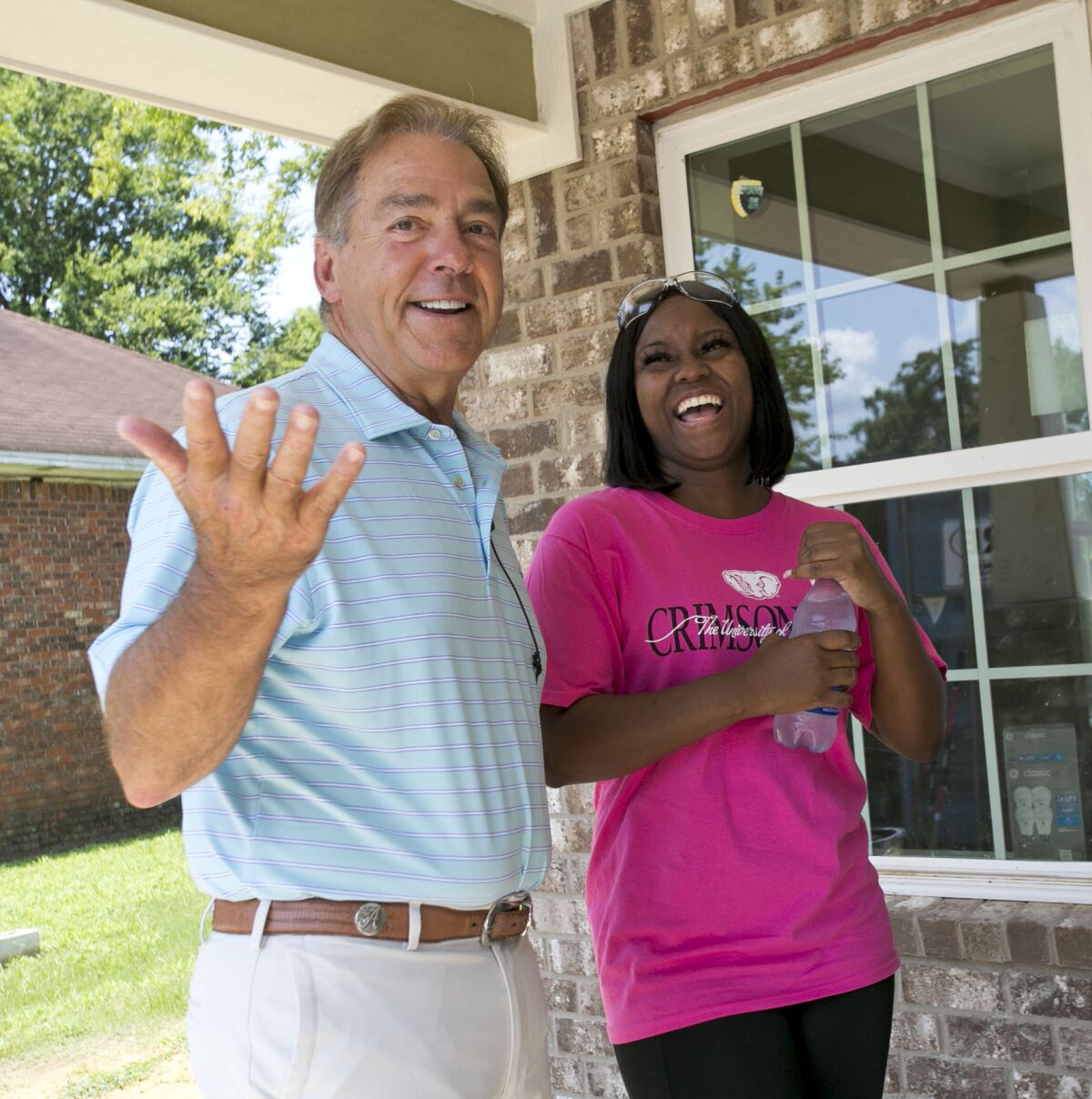 Twelve Alabama football players along with Coach Nick Saban and members of the staff helped with construction on the Habitat for Humanity Tuscaloosa's 18th Championship House funded by the Nick's Kids Foundation Tuesday, July 27, 2021, in Tuscaloosa, Alabama. Saban and homeowner Joselyn Hamner share a laugh on the front porch of her new house. (Gary Cosby Jr./The Tuscaloosa News via AP)