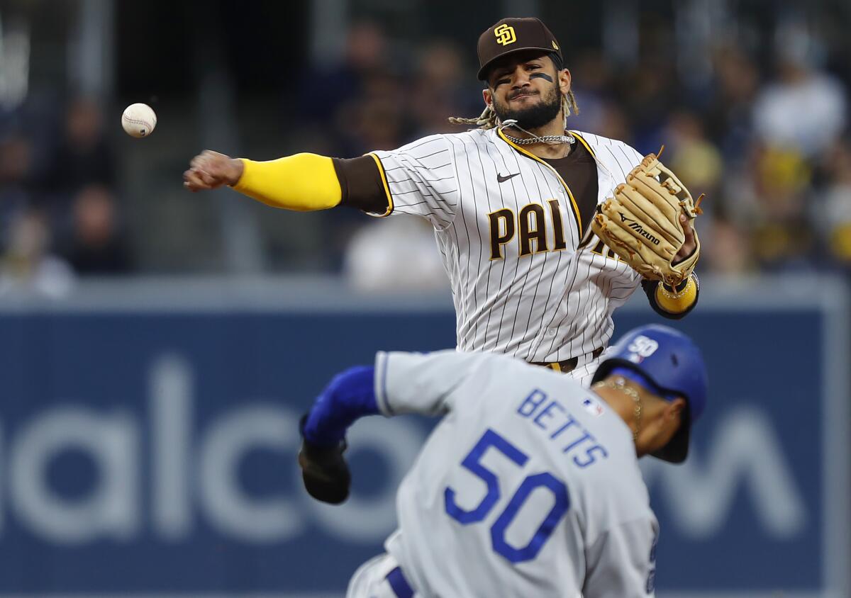 San Diego Padres shortstop Fernando Tatis Jr. turns a double play in front of Dodgers baserunner Mookie Betts.