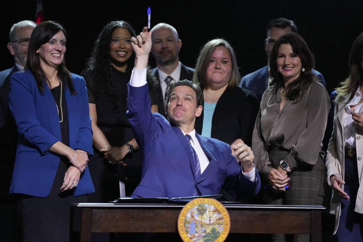 Surrounded by smiling fans, Florida Gov. Ron DeSantis throws a marker into the audience during a bill-signing event