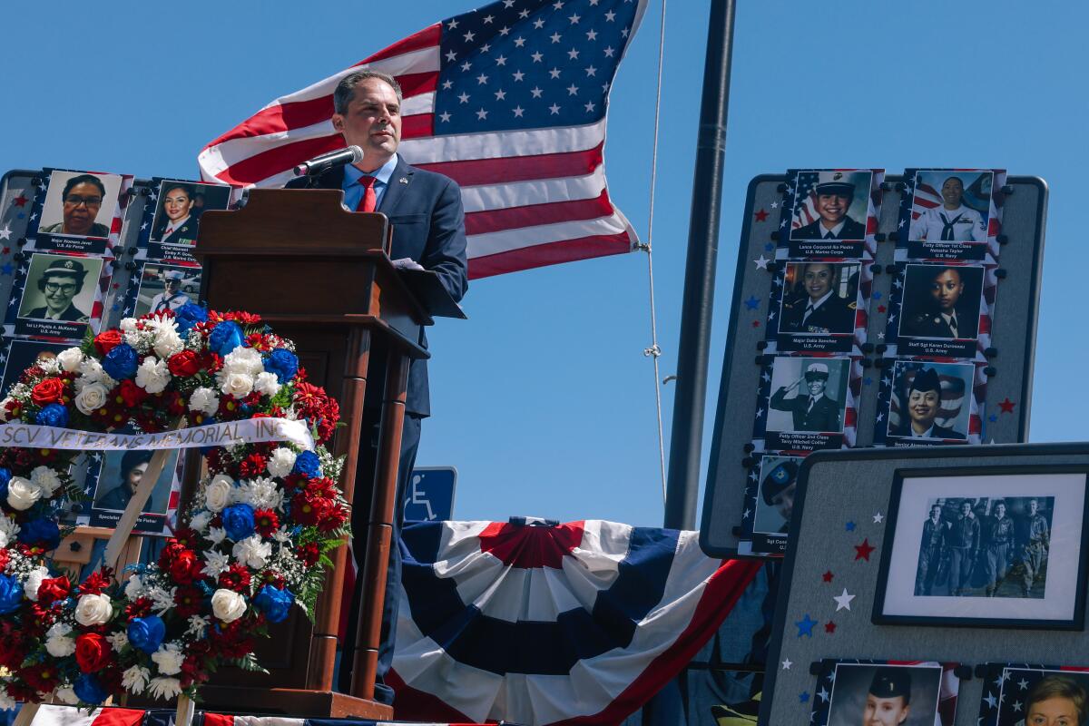 Rep. Mike Garcia standing at a lectern near photos, an American flag and a bunting