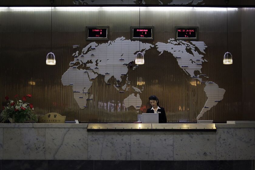 A hotel staff member stands at a reception desk decorated with a map of the world on the wall in Pyongyang on Oct. 23. North Korea has stepped up measures to prevent the spread of the Ebola virus.