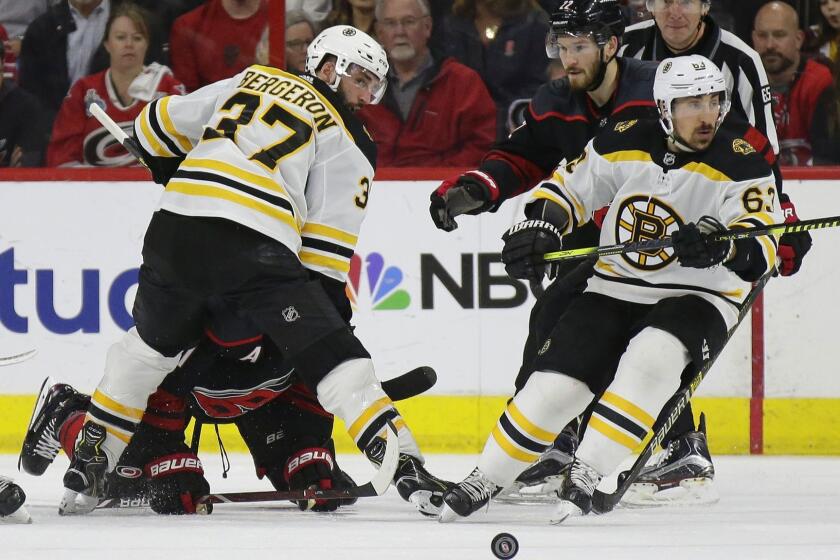 Boston Bruins' Patrice Bergeron (37) and Brad Marchand (63) skate for the puck with Carolina Hurricanes' Brett Pesce (22) and Jordan Staal during the second period in Game 3 of the NHL hockey Stanley Cup Eastern Conference final series in Raleigh, N.C., Tuesday, May 14, 2019. (AP Photo/Gerry Broome)