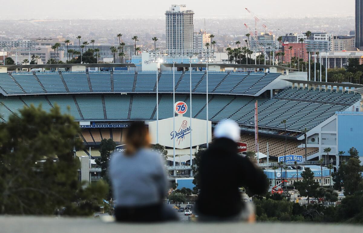 People sit on a hill overlooking Dodger Stadium on what was supposed to be Major League Baseball's opening day on March 26.