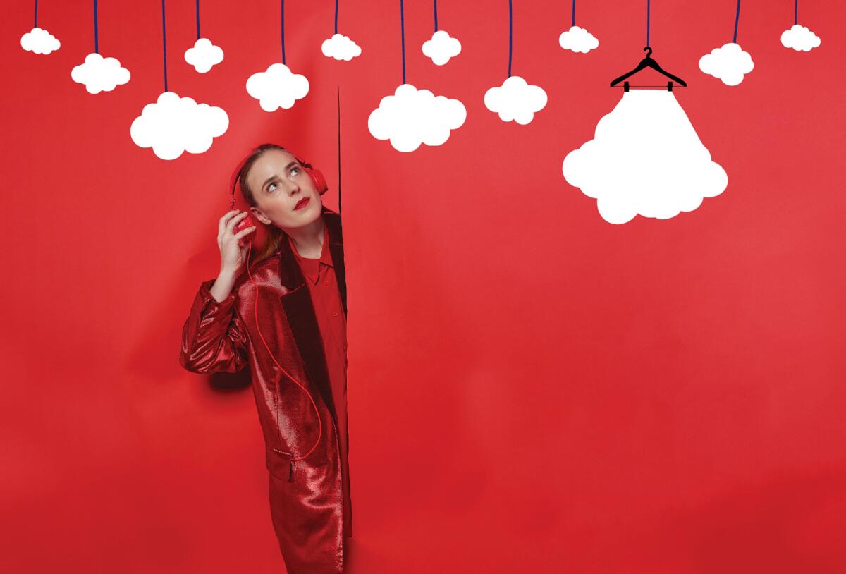 Jenn Freeman stands in front of a red background with clouds on it.