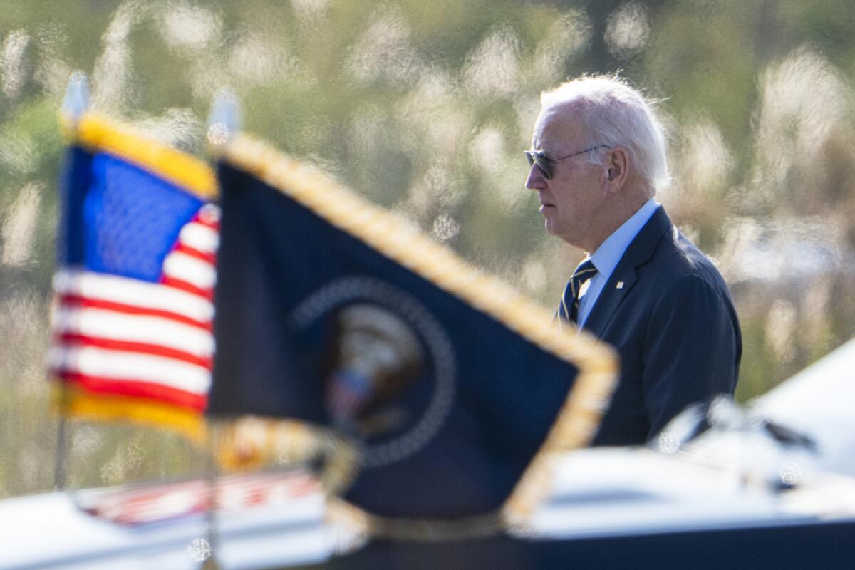 President Biden behind U.S. and presidential flags 
