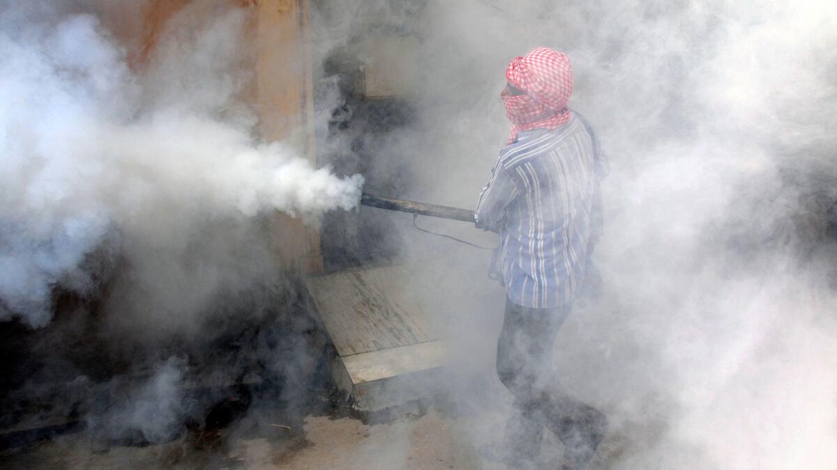 A worker fumigates a locality to kill mosquitoes at a location in New Delhi, India.