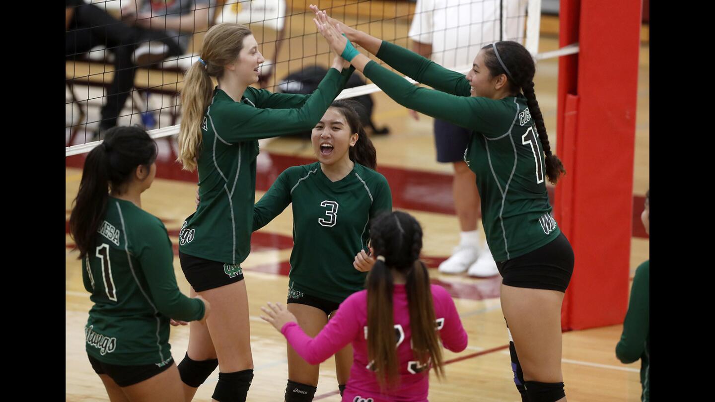 Costa Mesa High girls' volleyball players celebrate a point against Estancia during the second set in an Orange Coast League match at Estancia High on Tuesday, Sept. 25.