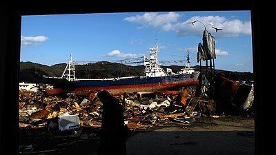 A window provides a view of a large ship sitting amid debris in Kesennuma.