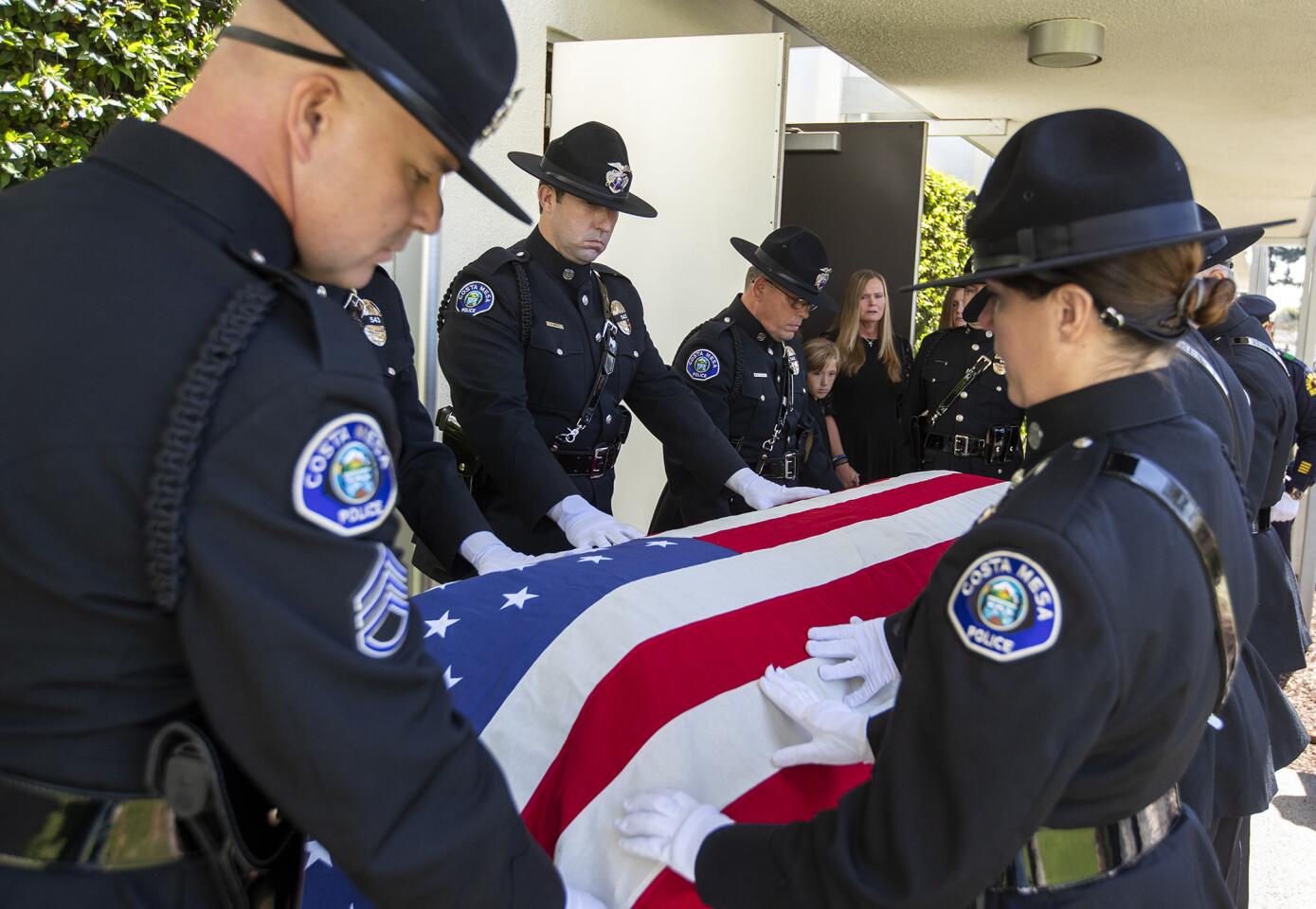 Pallbearers place an American flag over the casket of Costa Mesa police Officer Oscar Reyes as his wife, Jennifer, son Brandon, 10, and daughter Ashley, 15, look on during Reyes' funeral at Christ Cathedral in Garden Grove on Friday.